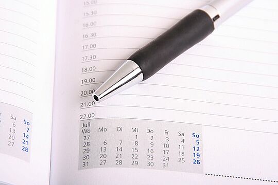Ein Photo. Zu sehen ist der Ausschntit eines Kalenders und ein daraufliegender Kugelschreiber.
